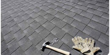 A hammer, gloves and nails on the roof of a house.