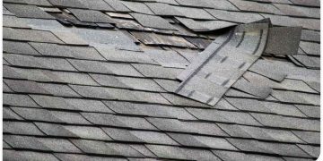 A damaged roof with missing shingles and broken gutter.