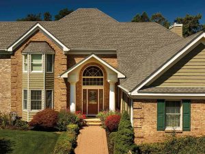 A large house with a brick front and a green roof.